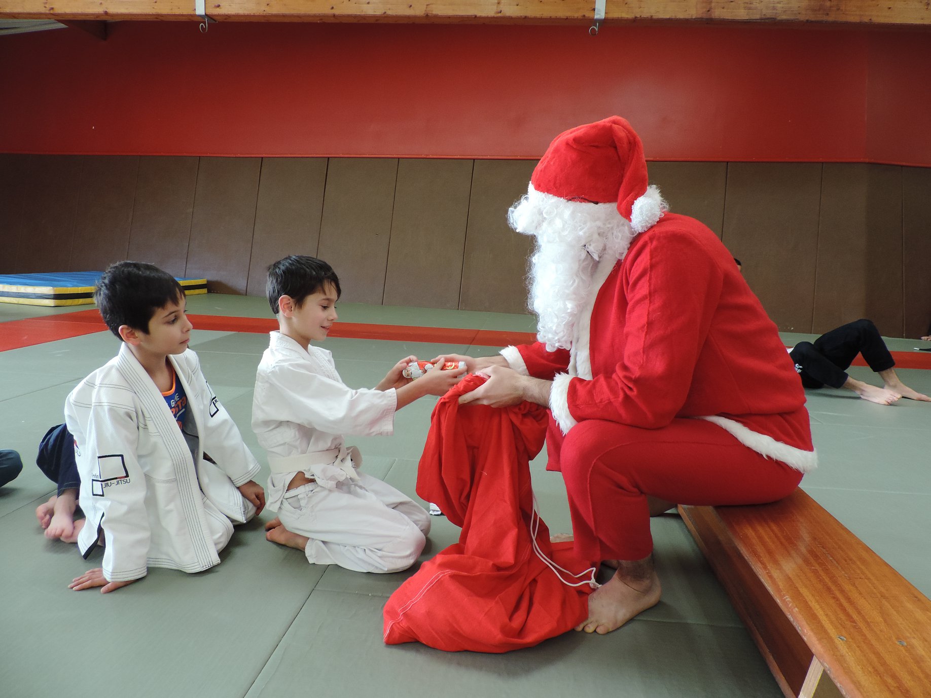 Père Noël distribuant des cadeaux à des enfants chez infini jiujitsu